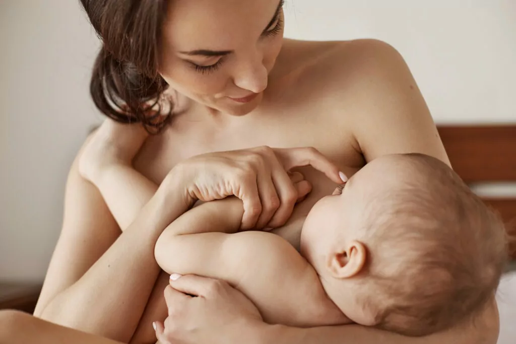 Young Tender Nude Mother Breastfeeding Hugging Her Newborn Baby Sitting Bed Morning 1024x683.Jpg